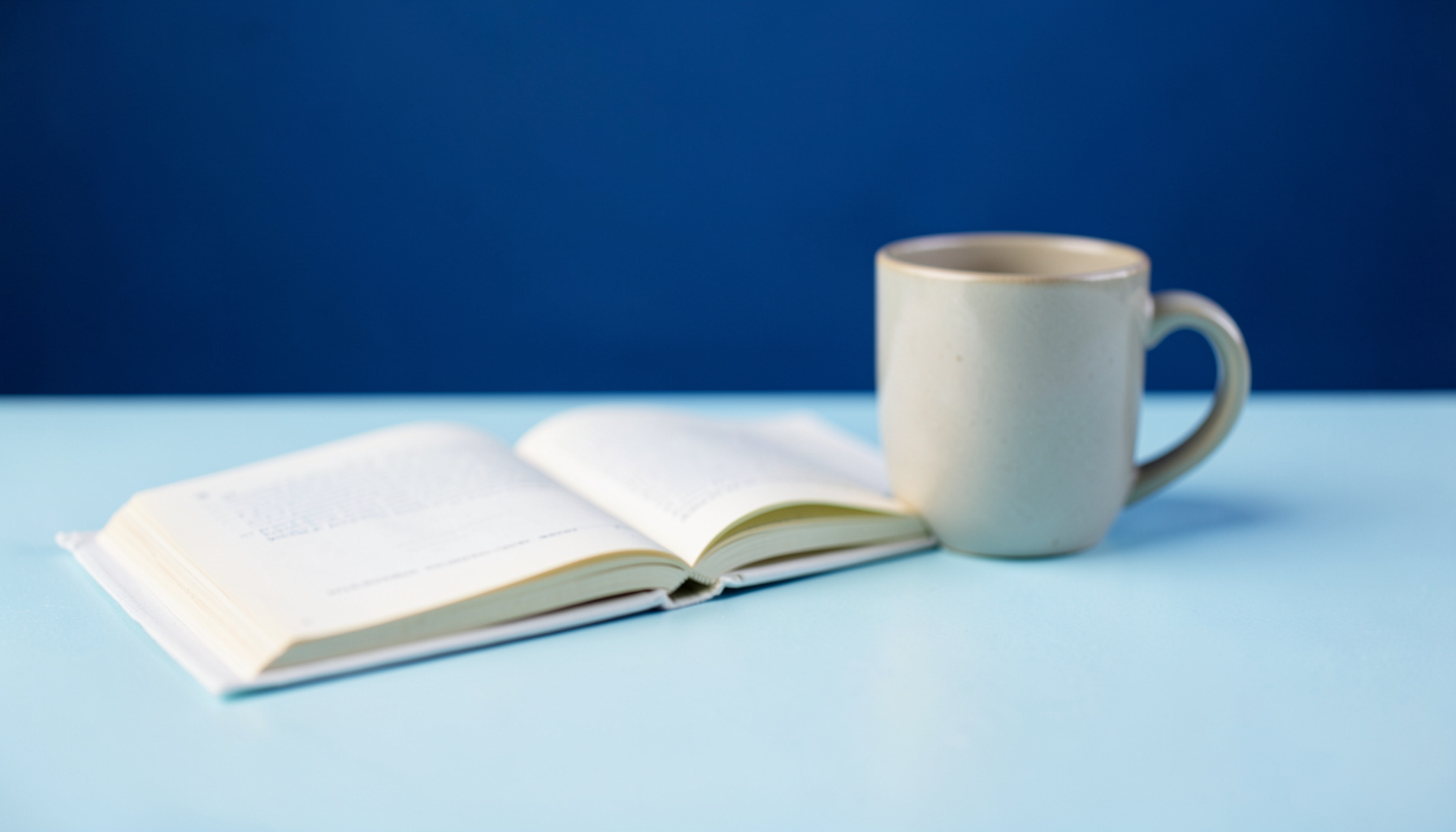 Soft-focus photograph of an open notebook beside a ceramic mug on a pale blue surface, suggesting quiet community reflection.